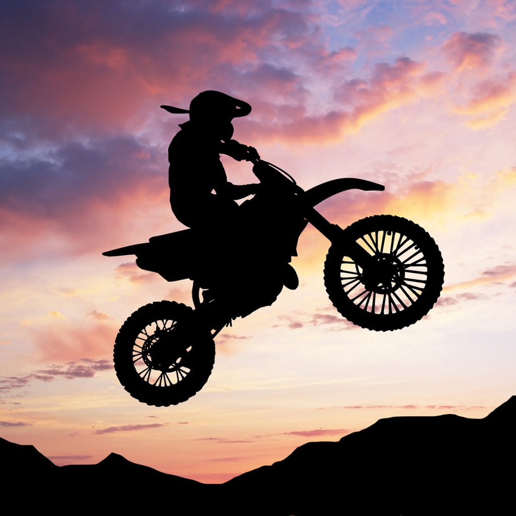 Moto da cross che fa un acrobazia con per sfondo il cielo rosa