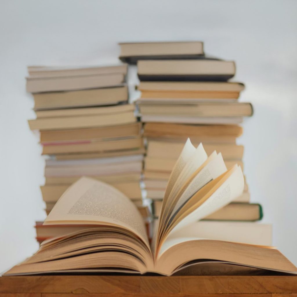 Pila di libri scolastici con libro aperto in primo piano